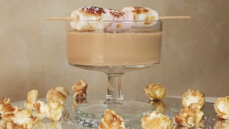 A-sweet-sugary-coffee-cocktail-with-charred-marshmallows-and-caramel-popcorn-rotating-on-a-turn-table-with-a-terra-cotta-background
