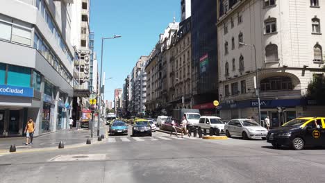 Panoramic-of-Corrientes-Avenue-under-Summer-Sunlight-City-Streets-Car-Traffic-Pedestrians-and-Skyline-in-Famous-Central-Landmark