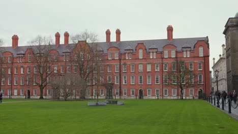 Green-campus-square-with-red-brick-wall-Trinity-College,-handheld-establisher
