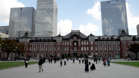 iconic-and-classic-railway-station-building-in-the-Marunouchi-shopping-district-in-Chiyoda,-Tokyo,-Japan,-with-the-esplanade-crowded-with-people-wearing-masks