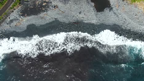 Road-and-black-sand-beach-washed-by-ocean-waves-in-Maui-Hawaii,-top-down-view