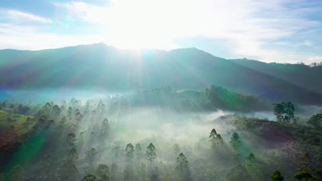 Aerial-drone-view-Sun-rays-super-falling-behind-mountain-and-fog-is-visible