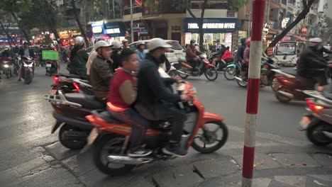Busy-intersection-in-Hanoi,-Vietnam,-with-scooters-negotiating-traffic