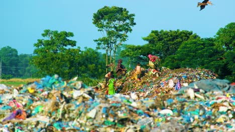 Group-of-colourful-rag-picker-workers-hunting-in-landfill-garbage-waste-for-clothing