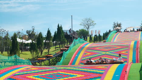 People-Ride-Donuts-on-Dry-Slide-At-Mongo-Land-in-Da-Lat,-Vietnam-in-Slow-Motion