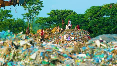 Scavenger-rag-picker-children-foraging-around-dirty-landfill-garbage-pile-as-bulldozer-leaves-site