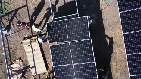 Aerial-drone-view-of-men-fitting-solar-panels-in-line-and-supplying-wires