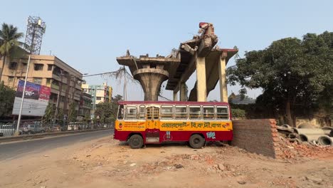 Shot-of-an-abandoned-bus-kept-under-a-broken-flyover-during-afternoon-in-Kolkata,-India