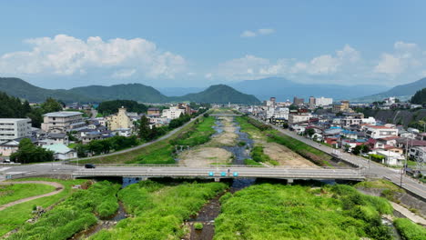 Aerial-pull-back-shot-over-the-Yomase-river,-summer-in-the-Yudanaka-town,-Japan