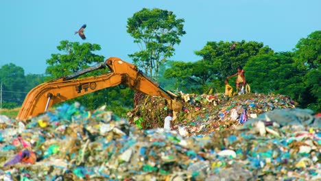 Menschen-Und-Bagger-Sortieren-Eine-Mülldeponie-In-Bangladesch