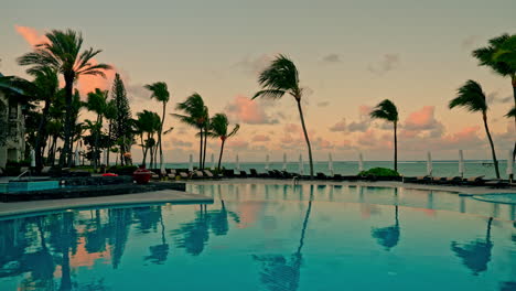 Beach-resort-with-outdoor-swimming-pool-and-high-palm-trees-at-sunset