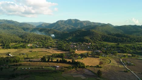 Golden-Rice-Fields-Mountain-Village-in-the-Valley-surrounded-by-Green-Forest-and-Mountains,-Mueang-Khong-in-the-Evening,-Drone-of-Small-Village-in-the-Mountains