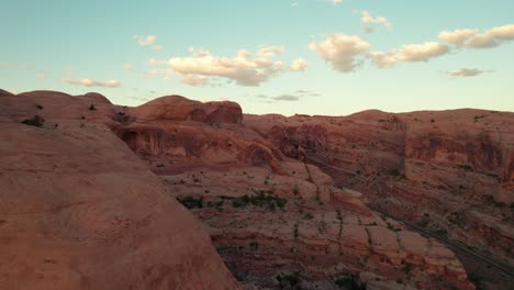 Distant-panning-drone-shot-over-Corona-Arch-in-Moab,-Utah-at-sunset