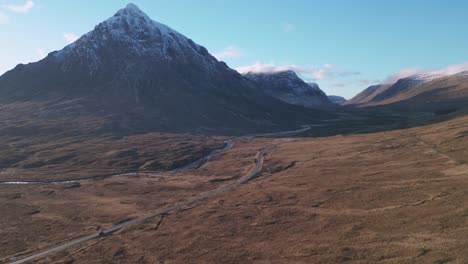 Glencoe-with-snow-capped-mountain-peak-and-winding-road-in-Scottish-Highlands,-serene-nature