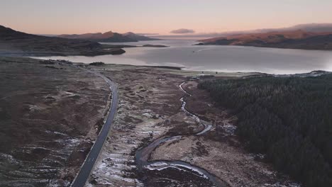 Winding-road-on-Isle-of-Skye-with-lochs-and-hills-during-twilight,-aerial-view