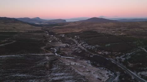 Winding-road-in-the-rugged-landscape-of-Skye-during-twilight,-aerial-view