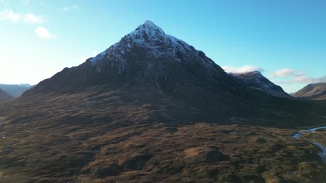 Snow-capped-mountain-peak-in-Glencoe-with-blue-skies,-aerial-view