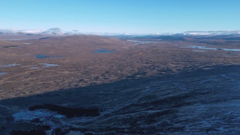 Rugged-Glencoe-landscape-with-scattered-lochs-under-blue-skies,-aerial-view