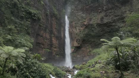 Aerial-pulls-out-from-dramatic-Coban-Sriti-Waterfall,-Kapas-Biru-Java