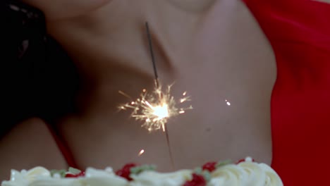 Eine-Geburtstagstorte-Mit-Einer-Feuerwerkskerze-Darauf-Für-Das-Feiernde-Mädchen-In-Einem-Roten-Kleid