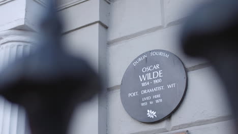 Closeup-profile-view-of-sign-board-at-entrance-of-Oscar-Wilde-House-with-blurred-foreground-in-Dublin,-Ireland