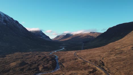 Vast-Scottish-Highland-valley-with-winding-river-and-road,-early-morning-light,-aerial-view