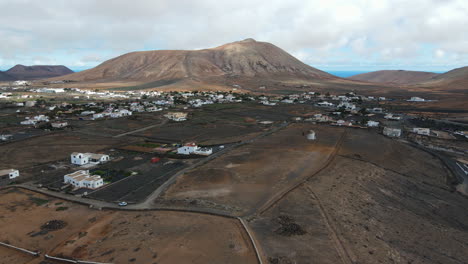 Traditional-La-Oliva-town-old-windmill-aerial-view-rising-over-scenic-volcanic-mountain-landscape-of-Fuerteventura