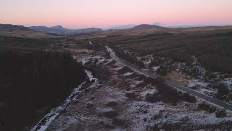 Winding-road-through-a-snowy-landscape-at-twilight,-Skye,-aerial-view