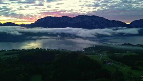 Colorful-sunrise-beyond-the-silhouettes-of-Alps-in-Austria-with-morning-clouds-over-a-lake