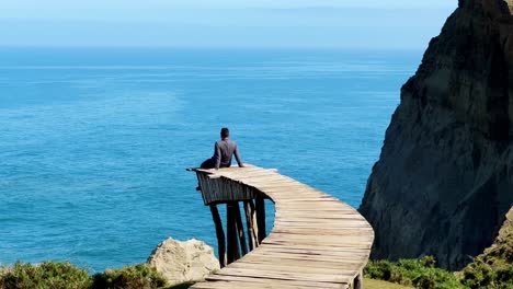 A-Person-Relaxes,-Sit-at-Muelle-de-las-Almas-Dock-Sea-Patagonia-Mountain-Landscape