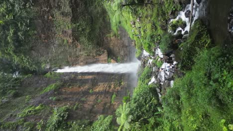 Touristen-Versammeln-Sich-Auf-Rauem-Gelände-Unterhalb-Des-Wasserfalls-Kapas-Biru-Auf-Java