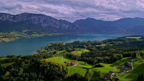 Drone-view-of-the-clear-lake-in-Austria-on-a-sunny-day-with-the-Alps-in-the-background