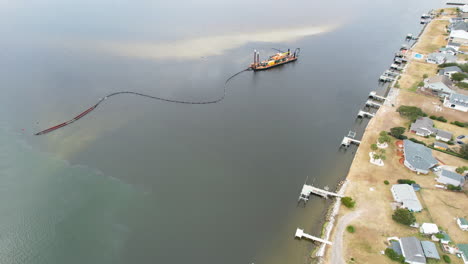 Drone-shot-of-dredging-happening-in-the-intercostal-waterway,-rotating-wide-angle