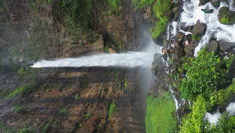 Vertical-format-low-aerial-in-canyon-at-Kapas-Biru-high-flow-waterfall