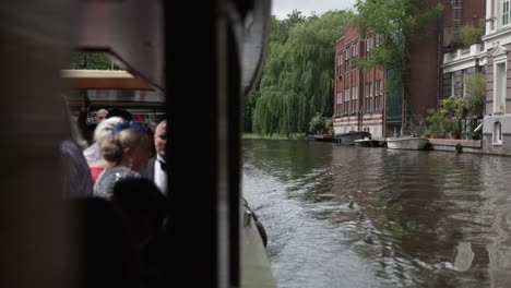 Eine-Bootsfahrt-Durch-Das-Niederländische-Stadtbild-Von-Amsterdam-Unter-Einer-Brücke,-Die-Das-Historische-Stadtbild-Als-Traditionelles-Fortbewegungsmittel-Auf-Dem-Wasser-Zeigt