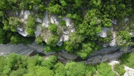 Aerial-top-down-view-of-the-Papingo-Rock-Pools,-also-known-as-ovires,-natural-green-water-pools-nestled-in-a-small,-smooth-walled-gorge-near-the-village-of-Papingo-in-Zagori-region-of-Epirus,-Greece
