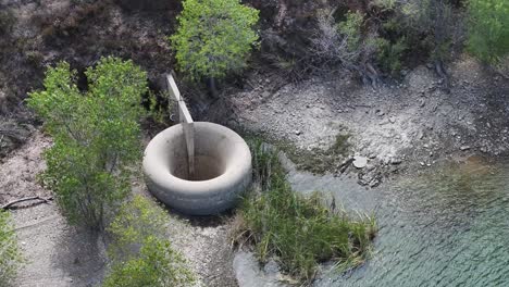 concrete-drainage-hole-in-bouquet-reservoir-Santa-Clarita-California-AERIAL-TELEPHOTO-ORBIT-60fps