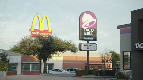 Mid-shot-of-Taco-Bell-and-McDonald's-signs-with-logos-outside-fast-food-chain-restaurants