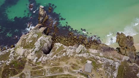Top-down-view-of-the-rocky-cliffside-of-North-of-France-on-the-edge-of-the-green-sea