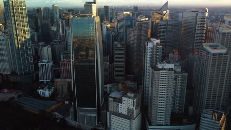 Aerial-view-in-front-of-contemporary-skyscrapers-of-Makati-city,-sunset-in-Manila,-Philippines