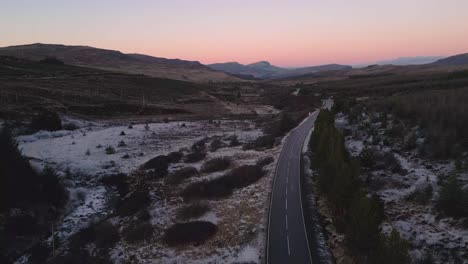 Winding-road-in-Skye-during-twilight-with-snow-patches-and-serene-landscape