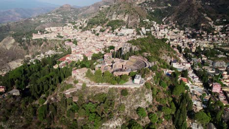 Drone-flying-towards-a-Colosseum-amphitheater-over-Taormina's-old-town
