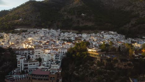 White-buildings-and-sunset-glow-over-township-of-Mijas,-aerial-view