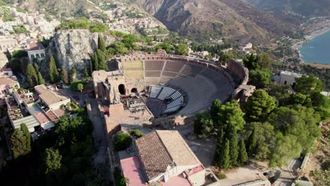 Drone-orbiting-around-a-colosseum-amphitheater-over-Taormina's-old-town