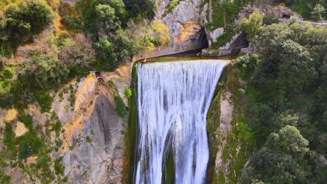 Drone-shot-ascending-while-panning-down-of-a-waterfall-near-Tivoli,-Italy