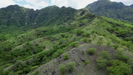 Drone-flying-along-the-beginning-of-a-mountain-ridge-covered-with-green-vegetation