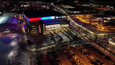Aerial-circulating-around-Saab-Arena-entrance-in-Linköping-city---People-queueing-in-snowy-winter-conditions