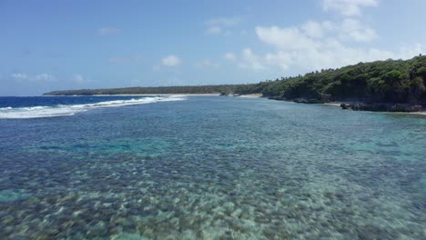 Drone-Shot-of-Coral-Reefs-by-Green-Coastline-of-Tropical-Island,-Tonga,-Polynesia,-Oceania