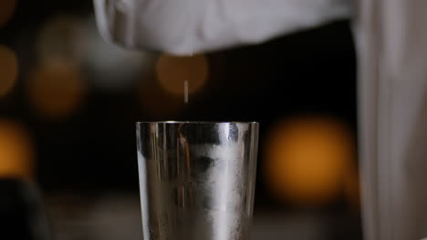 Closeup-shot-of-a-bartender-opening-up-a-cocktail-shaker-after-mixing-it