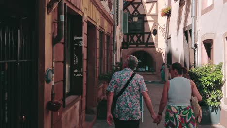 older-couple-walking-hand-in-hand-trough-shopping-alley-in-petite-france-strasbourg